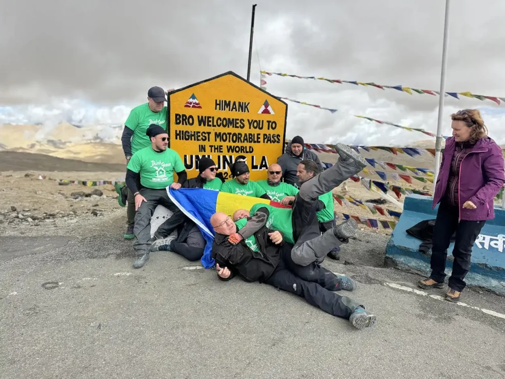 Riders and the Leh ground crew in matching green shirts at the Umling La sign (5,798 m), Ladakh