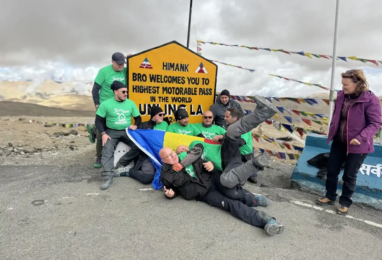 Riders and the Leh ground crew in matching green shirts at the Umling La sign (5,798 m), Ladakh